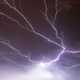 A closeup of lightning bolts spreading across the sky and turning it purple.
